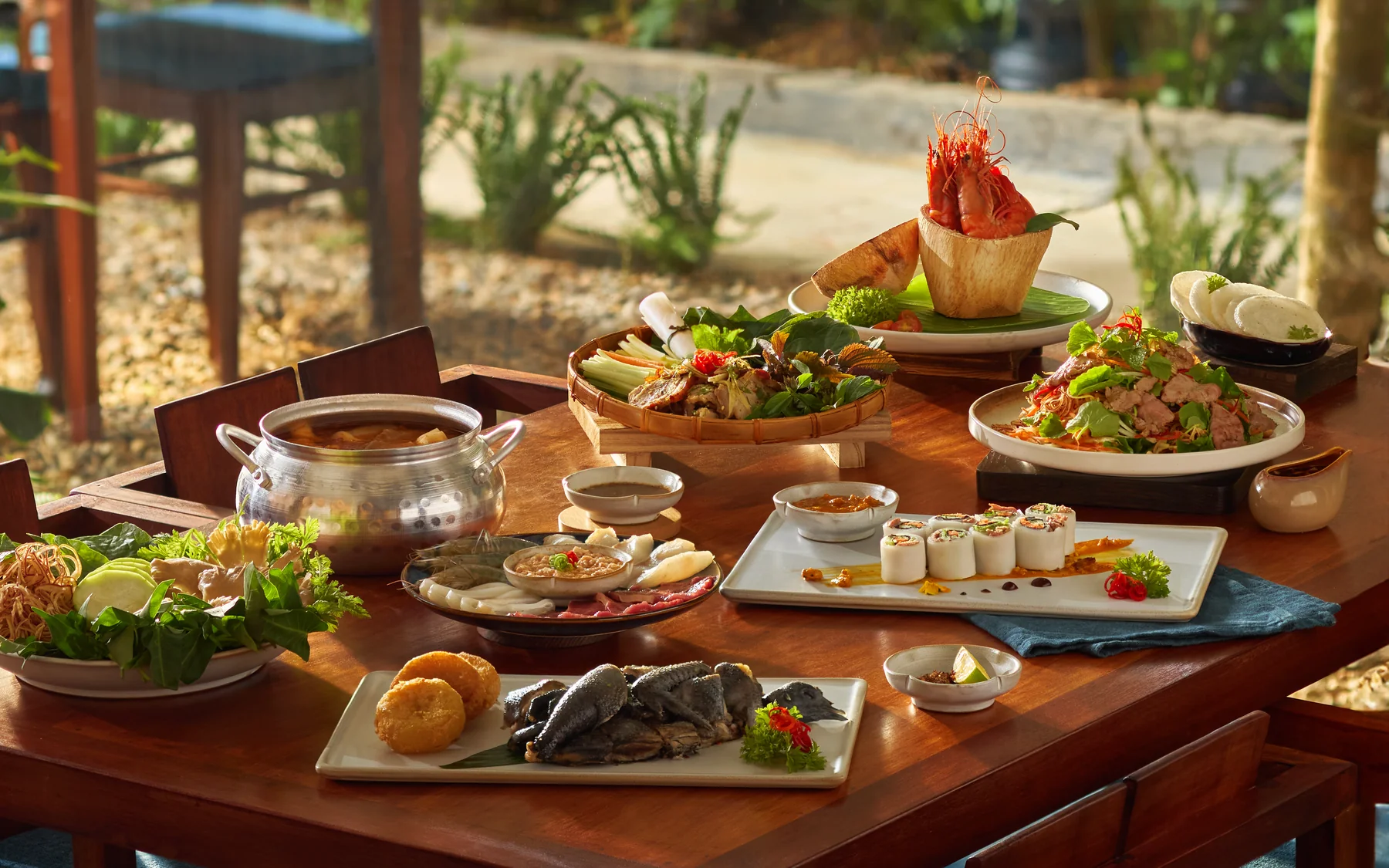 A MiRi Hôm table set with shared dishes, hotpot, herbs and dipping sauces